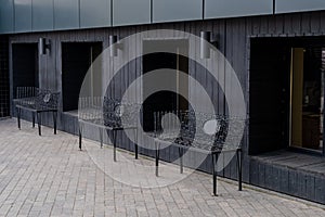 Beautiful and unusual black benches near the black wall and windows