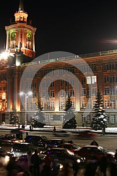 Beautiful urban winter night landscape, clock tower, Christmas trees covered with snow, lamppost with lights