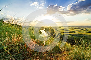 A beautiful valley with a river, blue sky with large clouds and bright sun. Aerial