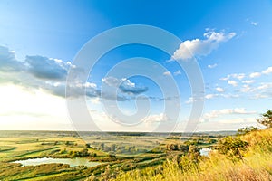 A beautiful valley with a river, blue sky with large clouds and bright sun. Aerial 4K UHD