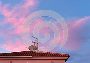 Beautiful vanilla sky with pink and red clouds over the roof