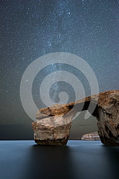 A beautiful vertical Milky Way night sky landscape photograph of the famous Azure Window rock arch