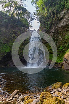 Beautiful vertical shot of a waterfall flowing through a mossy rough cliff in Xico, Veracruz, Mexico photo