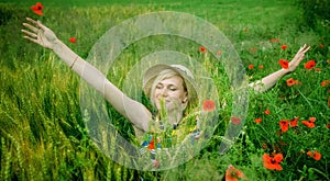 Beautiful very happy blonde woman with arms outstretched in a wheat field in summer sun`s rays. Horizontal image