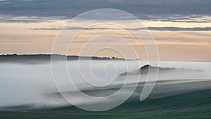 Beautiful vibrant landscape image of sea of fog rolling across South Downs English countryside during Spring sunrise