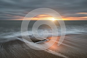 Beautiful vibrant sunset landscape image of Burton Bradstock golden cliffs in Dorest England