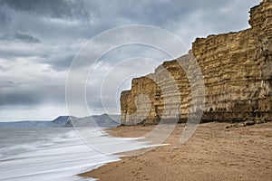 Beautiful vibrant sunset landscape image of Burton Bradstock golden cliffs in Dorest England