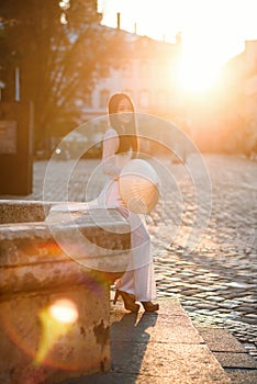 Beautiful Vietnamese girl dressed in traditional white Ao Dai dress stands near the fountain at the background of