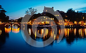 Beautiful view of Amsterdam canals with bridge and typical dutch houses.