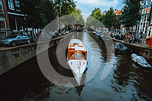 Beautiful view of Amsterdam canals with white cruise boat bridge and typical dutch houses. Holland