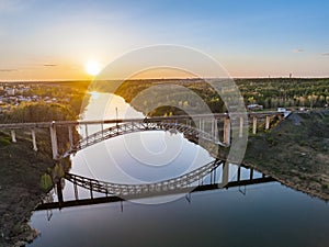 Beautiful view of the arched railway bridge across the Iset River in the city of Kamenkk-Uralsky at sunset in spring. Kamensk-