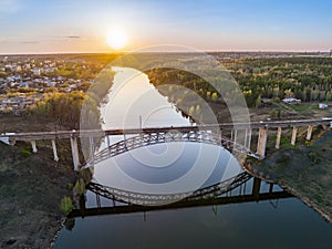 Beautiful view of the arched railway bridge across the Iset River in the city of Kamenkk-Uralsky at sunset in spring. Kamensk-