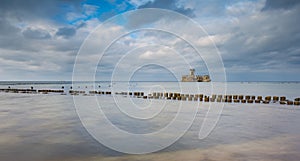 Beautiful view on Baltic sandy coast with old military buildings from world war II and wooden breakwaters.