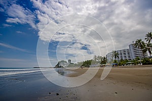 Beautiful view of the beach with sand, and buildings behind in a beautiful day in with sunny weather in a blue sky in Same, Ecuado