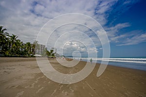 Beautiful view of the beach with sand, and buildings behind in a beautiful day in with sunny weather in a blue sky in Same, Ecuado