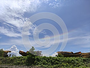 beautiful view of blue sky with a little rainbow over a parked heavy dump trucks