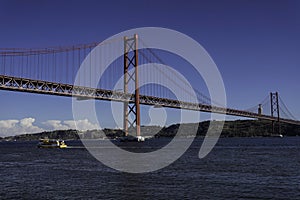 Beautiful view of the Bridge 25th of April over the river Tagus in the heart of Lisbon in Portugal. Small sailing boat and fishing