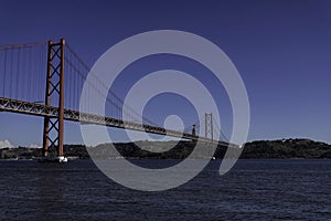 Beautiful view of the Bridge 25th of April over the river Tagus in the heart of Lisbon in Portugal. Small sailing boat and fishing