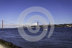 Beautiful view of the Bridge 25th of April over the river Tagus in the heart of Lisbon in Portugal. Small sailing boat and fishing