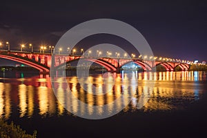 Beautiful view of a bright and colorful bridge across the river. Cityscape at night with a beautiful bridge over the river