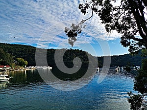 Beautiful view of a calm creek with reflections of blue sky, mountains and trees on water