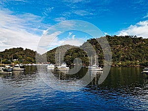 Beautiful view of a calm creek with reflections of blue sky, mountains and trees on water