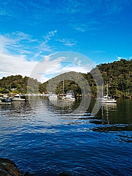 Beautiful view of a calm creek with reflections of blue sky, mountains and trees on water