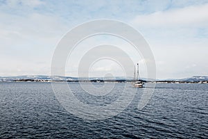 Beautiful view of calm sea, fjord and sailing boat, ship on cold winter day in Oslo
