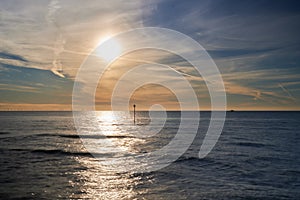 Beautiful view of a calm sea with the reflection of a bright sun on the surface during sunset