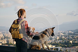 Beautiful view of the capital of Georgia Tbilisi from above from old town. A young man with two dogs admires the sunrise