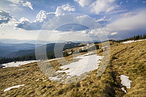 Beautiful view of Carpathian mountains in early spring. Hill with dry grass and spots on snow and fantastic panorama of distant fo photo