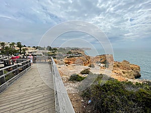 Beautiful view of the Carvoeiro Boardwalk with palm trees and cliffs along the sea in The Algarve