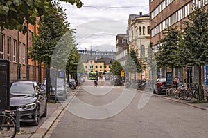 Beautiful view of city landscape on autumn day. Old colorful buildings, parked cars and bicycles, man on bike crossing road.