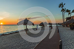 Beautiful view of coast line hotel area on sunset. White sand beach. sun umbrellas and palm trees on blue sky background.