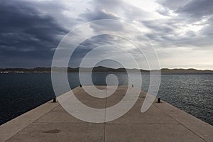 Beautiful view from a concrete pier at an island in the sea with cloudy sky in the evening