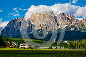 Beautiful view of Cortina d`Ampezzo town with alpine green landscape and massive Dolomites Alps in the background. Province of