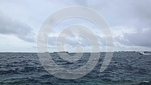 Beautiful view of dark blue water of Indian Ocean. White speedboat is passing by. Horizon line and white clouds on blue sky