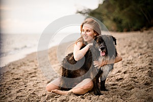 beautiful view of dog on the beach being hugged by young woman