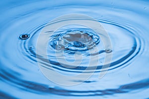 Beautiful view of drops making circles on blue water surface isolated on background