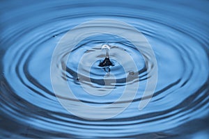 Beautiful view of drops making circles on blue water surface isolated on background