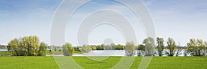 Beautiful view on a dutch landscape near the river Waal and Zaltbommel, water, green grass, meadows and trees on a sunny day