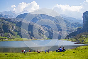 Beautiful view of Ercina Lake in Covadonga Lakes, Asturias, Spain. Green grassland with people relaxing and mountains at the