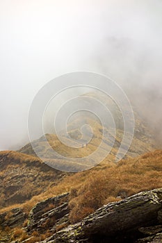 Beautiful view of Fagaras Mountains ridge with low clouds and hikers on the path