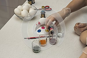 Beautiful view of female and  child hands prepare color for painting of traditional Easter eggs.