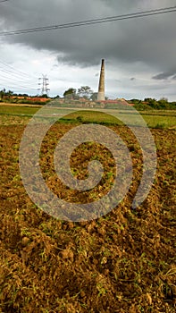 Beautiful view of the fields Briquette making chimney under the black cloud in India