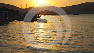 Beautiful view on fishing boats floating on sea surface with sunset at background. Fisherman vessels standing in bay