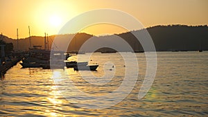 Beautiful view on fishing boats floating on sea surface with sunset at background. Fisherman vessels standing in bay