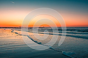 Beautiful view of the foamy waves on the beach under the sunset captured in Domburg, Netherlands