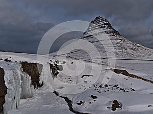 Beautiful view of frozen Kirkjufellsfoss waterfall near GrundarfjÃ¶rÃ°ur on SnÃ¦fellsnes, Iceland in winter with ice formations.