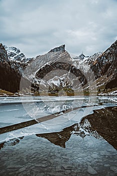 Beautiful view of a frozen Moraine lake with a reflection of surrounded snow covered mountains